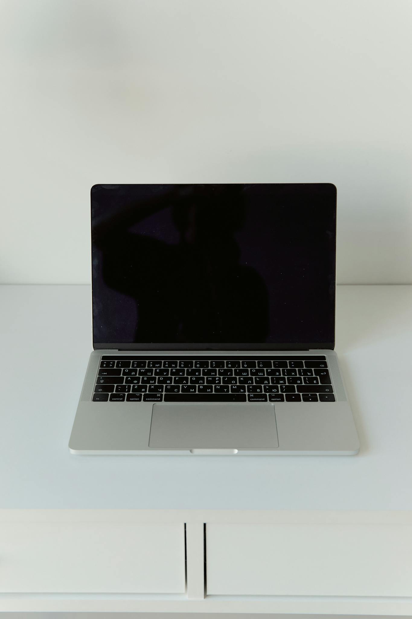 A modern laptop with a blank screen on a minimalist white desk background.