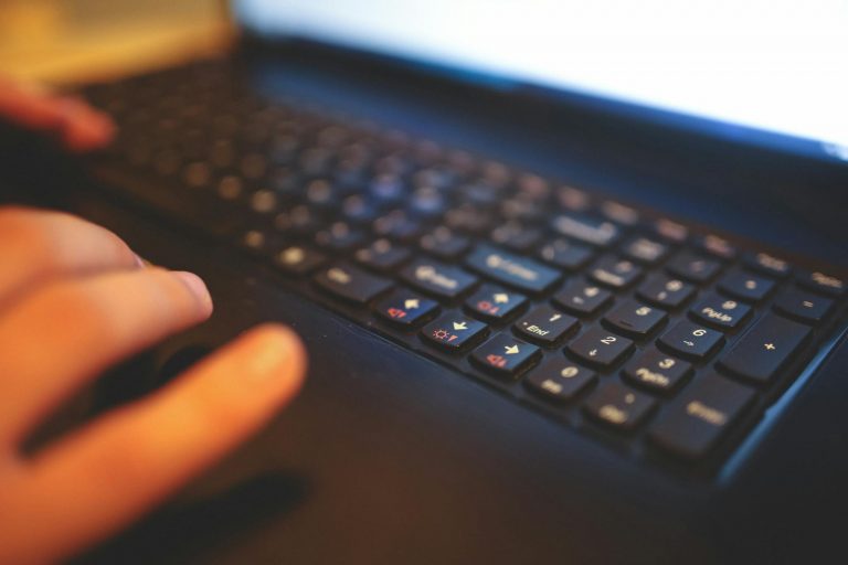 Blurred close-up of hands typing on a laptop keyboard, capturing a focused work moment.