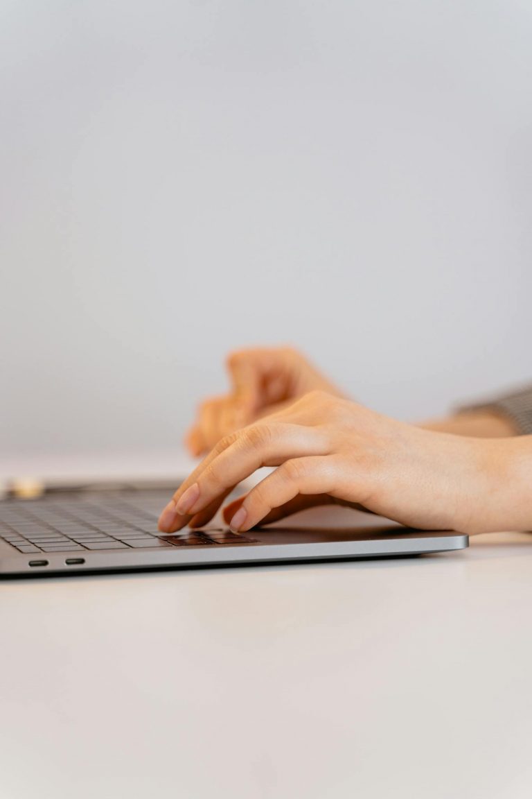 Hands typing on a laptop keyboard, focusing on digital connectivity and remote work.